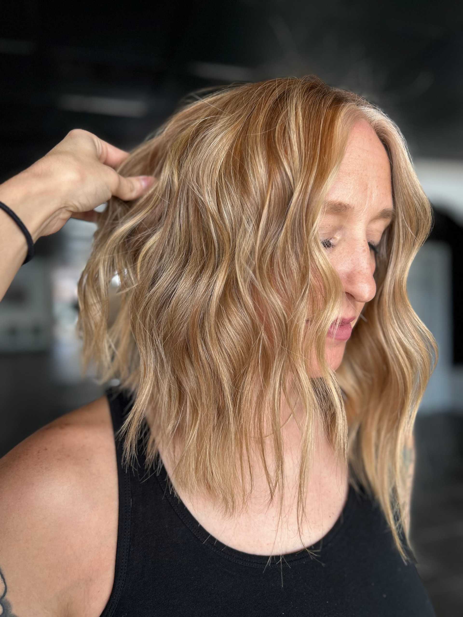 Short-haired woman with wavy blonde highlights, styled in a modern salon.
