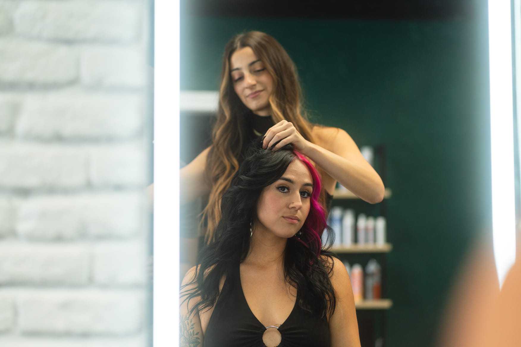 Hairdresser styling a woman's hair in a salon, with a focus on teamwork and skill.